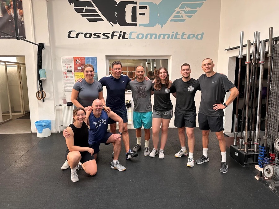 A small evening class posing under the CrossFit Committed logo