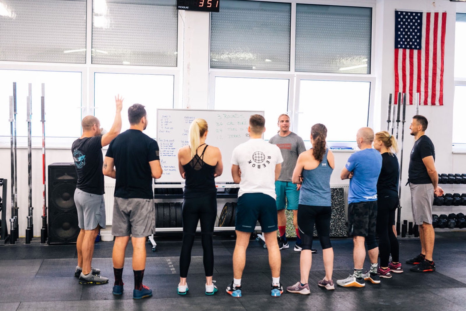 A coach walking a group through the weekly check-in at the whiteboard
